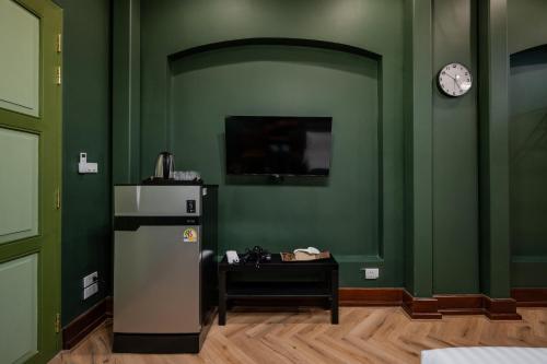 a green room with a refrigerator and a table at Arun Sa Wad - Yaowarat 27 in Bangkok