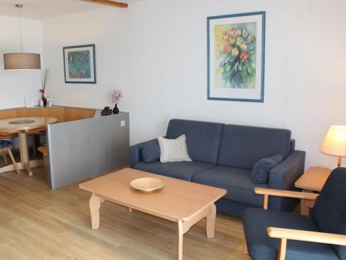 un salon avec un canapé bleu et une table dans l'établissement Ferienhaus Nr 38, Kategorie Komfort, Feriendorf Hochbergle, Allgäu, à Lechbruck am See