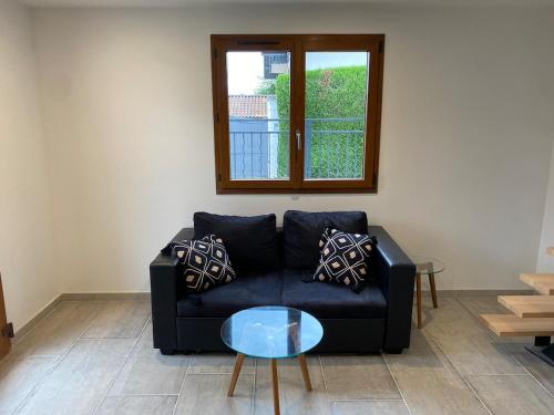 - un salon avec un canapé noir et une table en verre dans l'établissement Chalet de pécheur entièrement rénové, proche du Lac Léman, à Anthy