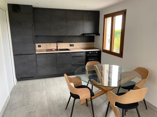 une cuisine avec une table et des chaises en verre dans l'établissement Chalet de pécheur entièrement rénové, proche du Lac Léman, à Anthy