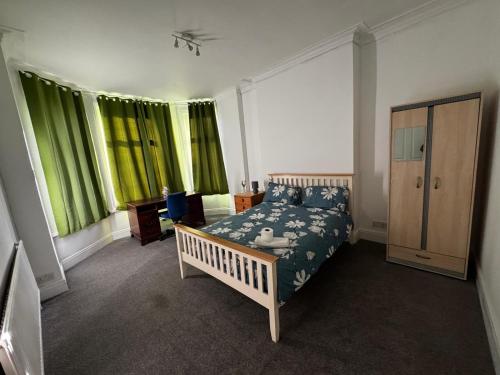 a bedroom with a bed and some green curtains at Ensuite Double-Bedroom in the Heart of Salford Manchester Perfect for Short Stays GCSW2 in Manchester