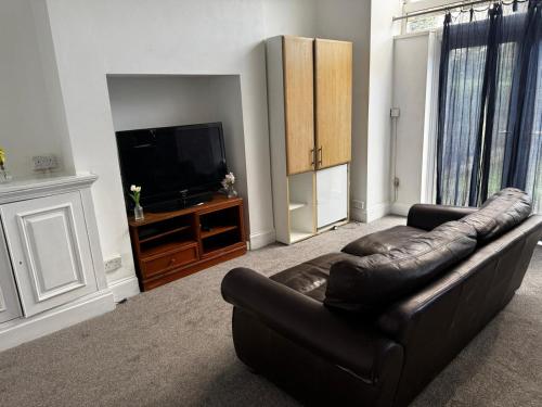 a living room with a leather couch and a flat screen tv at Ensuite Double-Bedroom in the Heart of Salford Manchester Perfect for Short Stays GCSW2 in Manchester
