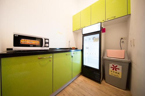 a kitchen with green cabinets and a microwave and a refrigerator at SleepBox Hostel in Taipei