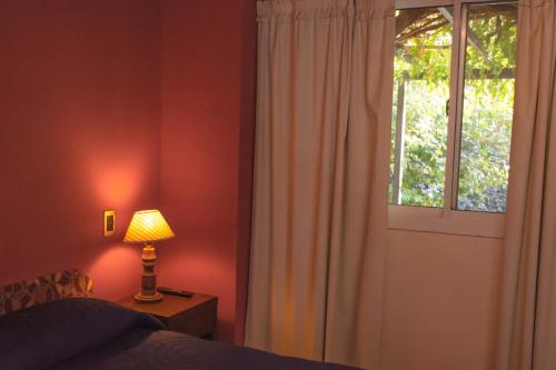 a bedroom with a bed and a window and a lamp at Alamo Hostel & Suites in Mendoza