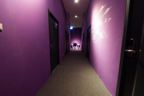 a purple hallway with two people in the background at SleepBox Hostel in Taipei