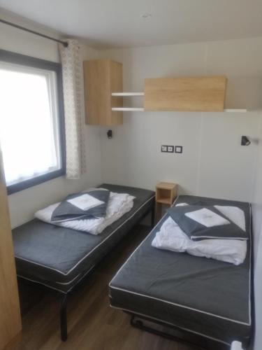 deux lits dans une petite pièce avec une fenêtre dans l'établissement MHVACANCES 2 LOUENT PLUSIEURS MOBILHOMES DANS CAMPING 4 ETOILES PROCHE CHATEAUX et ZOO BEAUVAL, à Onzain