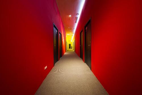 a corridor with red walls and a hallway with doors at SleepBox Hostel in Taipei