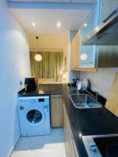 a kitchen with a washing machine and a sink at Big Studio Apartment in Dubai Marina Walking to JBR Beach, Cruise and DMCC Metro in Dubai