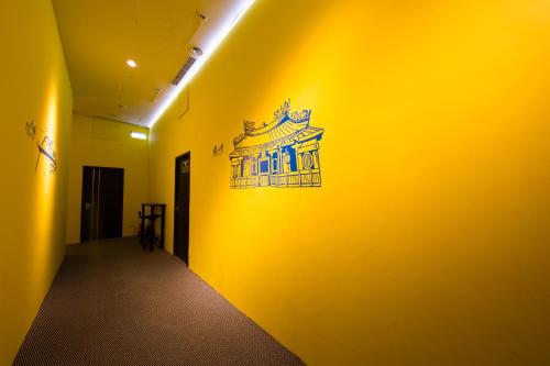 a hallway with a yellow wall with a sign on it at SleepBox Hostel in Taipei