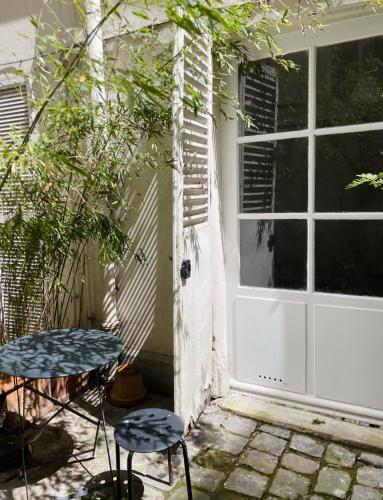 d'une terrasse avec une porte blanche et deux tabourets. dans l'établissement Chic neighborhood charming courtyard studio 7th, à Paris