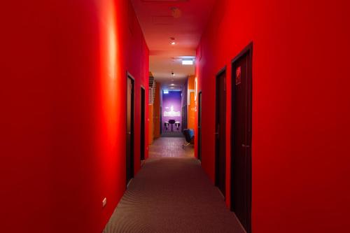 a hallway with red walls and a long hallway with doors at SleepBox Hostel in Taipei