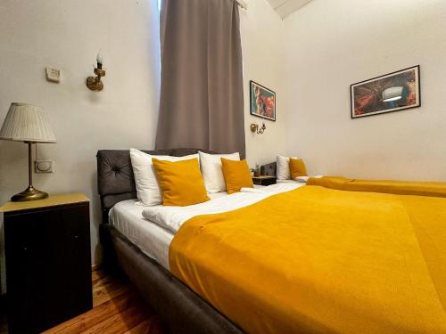 a bedroom with a large bed with yellow sheets at The Only One Suites in Niš