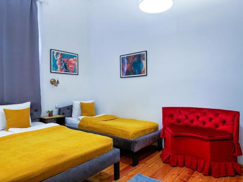 a room with two beds and a red chair at The Only One Suites in Niš