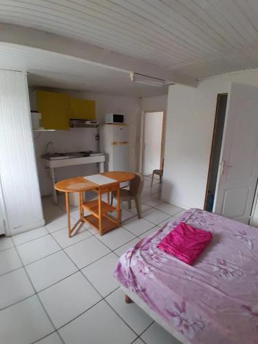 a bedroom with a bed and a table and a kitchen at Studio confortable à Les Abymes, 12m², balcon agréable in Les Abymes