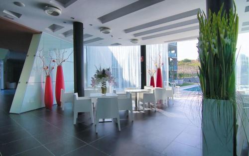 a restaurant with white tables and white chairs and plants at Apolo Suites Rentalmar in Salou