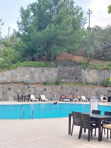 a pool with tables and chairs and people sitting around it at Dusler Vadisi Kazdaglari in Edremit
