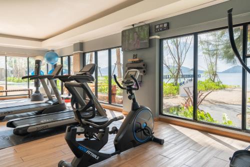 a gym with treadmills and ellipticals in a room with windows at Thavorn Beach Village Resort & Spa Phuket in Kamala Beach