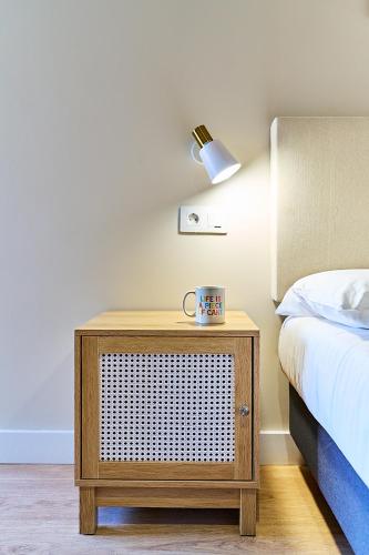 a bedroom with a bed and a night stand with a lamp at Apartamentos Delia by gaiarooms in León