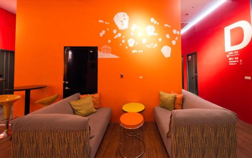 a living room with two couches and an orange wall at SleepBox Hostel in Taipei