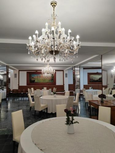 a dining room with white tables and a chandelier at Hotel Mio City in Kula