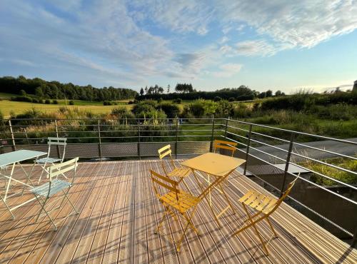 a wooden deck with a table and chairs on it at Les Gîtes de la Préale in Achet