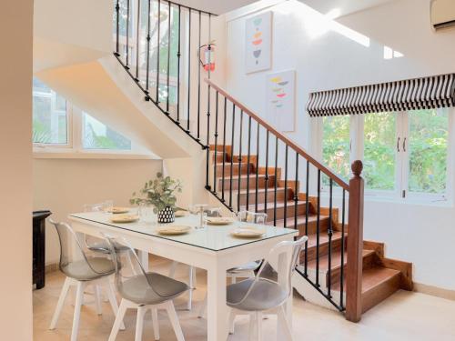 a dining room with a table and chairs and stairs at Rainforest - Casa Azure 5 Min walk to the beach in Calangute