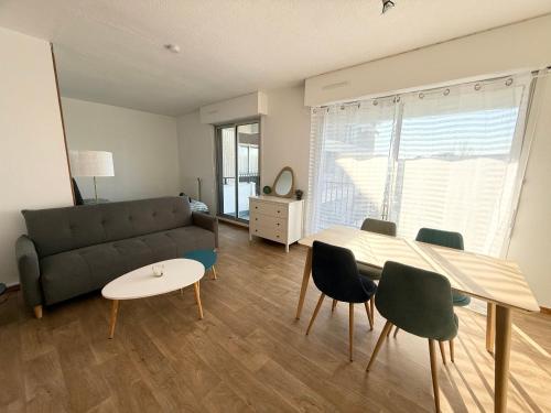 un salon avec un canapé, une table et des chaises dans l'établissement Le Cocon Urbain Balcon & Parking Privé, à Mérignac
