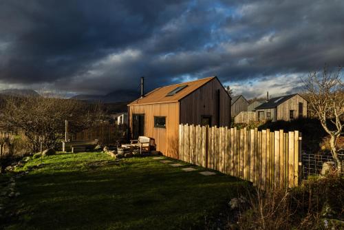 a wooden house in a yard with a fence at Jura - The Rusty Hut in Craighouse