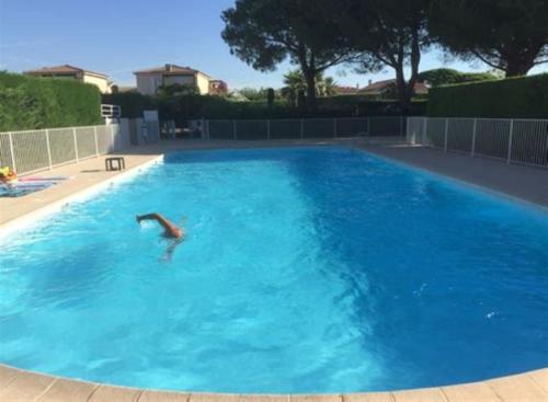 une personne nageant dans une grande piscine bleue dans l'établissement Loft lumineux et calme - terrasse - piscine, à Antibes