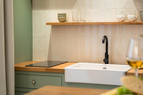 a kitchen with a sink and a glass of wine at Pinot Noir Apartments & Wine Bar in Nové Město nad Metují