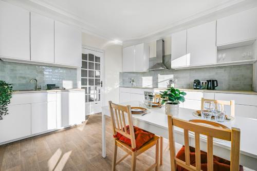 une cuisine avec des armoires blanches et une table et des chaises dans l'établissement Le Stella - Centre-Ville - Proche Gare - Wifi, à Chelles