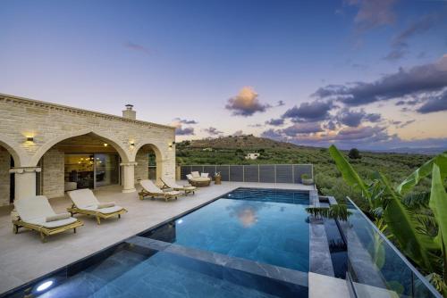 a swimming pool with lounge chairs and a house at Elegant Villa with Pool & Views in Áptera