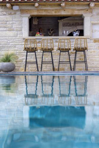 a couple of chairs sitting next to a swimming pool at Elegant Villa with Pool & Views in Áptera