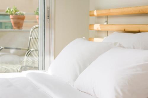 a bed with white pillows next to a window at Florentin House - By HOMY in Tel Aviv