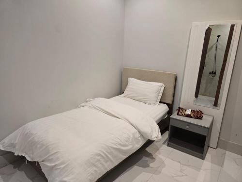 a white bedroom with a bed and a mirror at Single Room in Riyadh