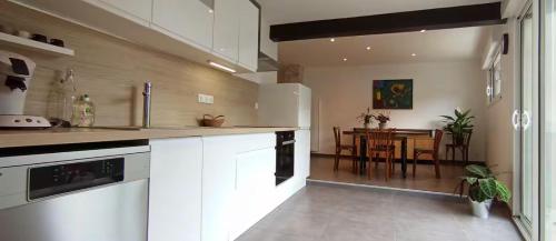 - une cuisine avec des placards blancs et une table à manger dans l'établissement Le Faubourg Gourdon, à Beaupréau