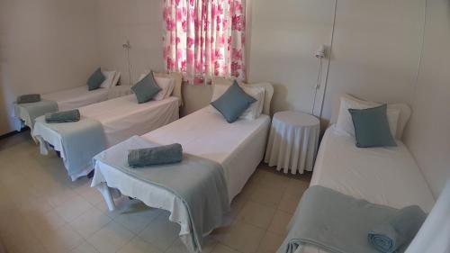 a room with three beds and two tables and a window at RAMBLiNN in Zinkwazi Beach