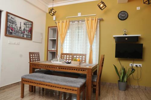 a dining room table with chairs and a television at AVANTI CASTELLO in Guruvāyūr