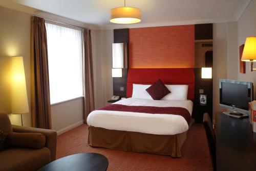 una camera d'albergo con letto e TV di The Dragon Hotel a Swansea