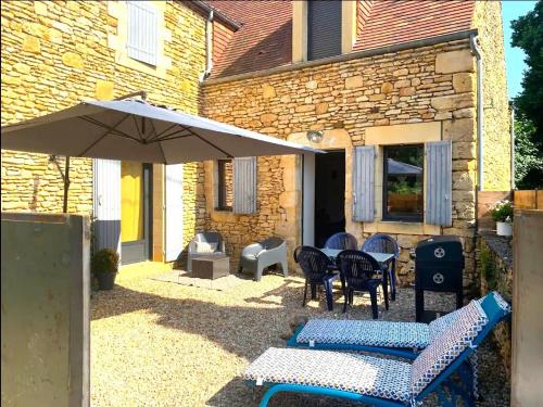 une terrasse avec un parasol, des tables et des chaises dans l'établissement PETIT PARADIS DE BARAN Romantic stone cottage with hot tub near Sarlat, à Finsac
