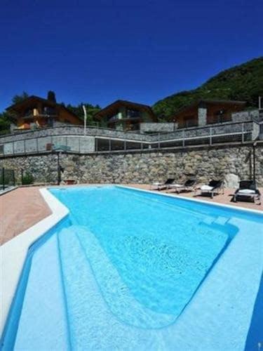 a large blue swimming pool with chairs and a building at CASA di SILVA tra MONTI e LAGHI PERLEDO REGOLEDO in Regoledo