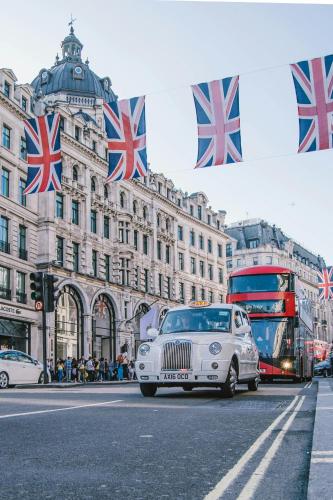 a white car driving down a street with british flags at Radisson Blu Hotel, London Bond Street in London