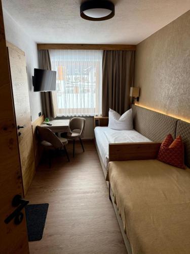 a hotel room with a bed and a desk at Pension Kristall in Flirsch