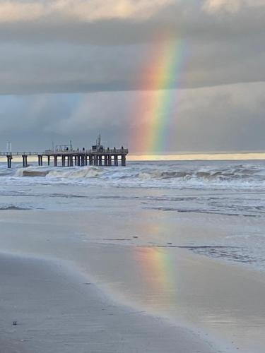 a rainbow over a beach with a pier and the ocean at Brisas 1 in Santa Teresita