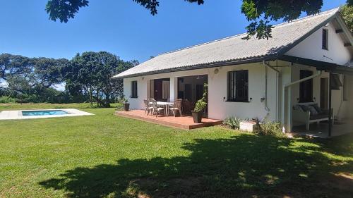 a small white house with a patio and a pool at RAMBLiNN in Zinkwazi Beach