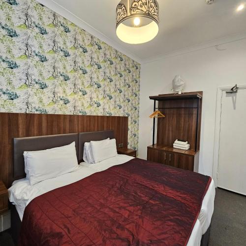 a bedroom with a large bed with a red blanket at Chelsea House Hotel - B&B in London