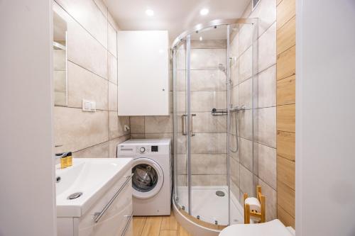 a bathroom with a sink and a washing machine at Apartament Szczecin - Kobalt Brama Portowa II in Szczecin