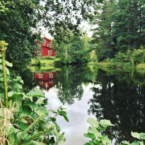 a red house is reflected in the water of a lake at Historiskt, mysigt boende med sjöutsikt i underbar miljö in Undenäs