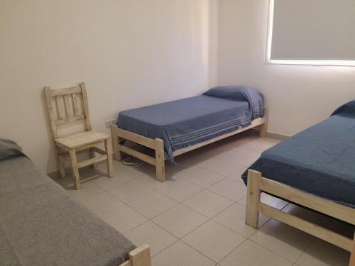a small room with two beds and a chair at Casa en La Punta San Luis in La Punta