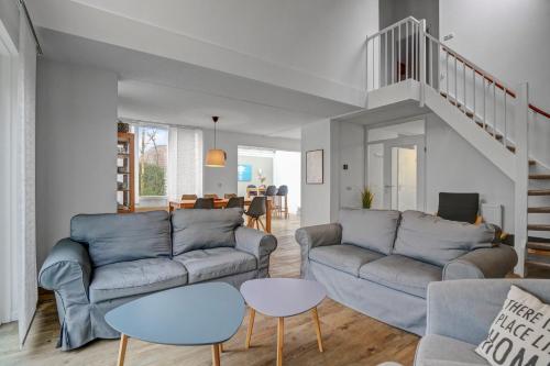 a living room with two couches and a staircase at Villa Beatrix - Landal park Ooghduyne Julianadorp aan Zee in Bruggenmors
